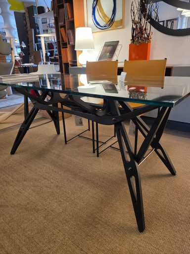 Tavolo Reale di Zanotta Modern glass-top desk with black legs and wooden chairs in a stylish interior.